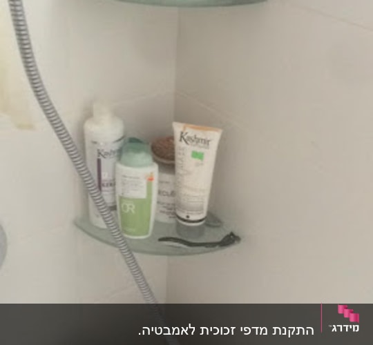 מדפי זכוכית בפינת מקלחת עם מוצרי טיפוח